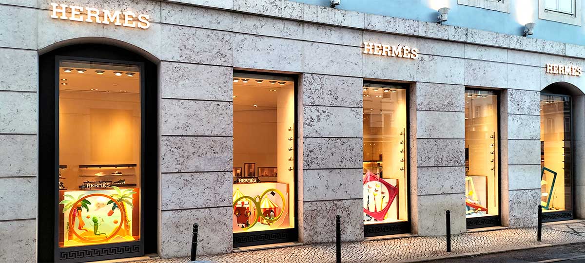 Fachada exterior de una boutique Hermès en Portugal con escaparates decorados
